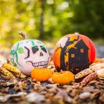 Painted pumpkins showing a haunted house and ghost in a pile of autumn leaves